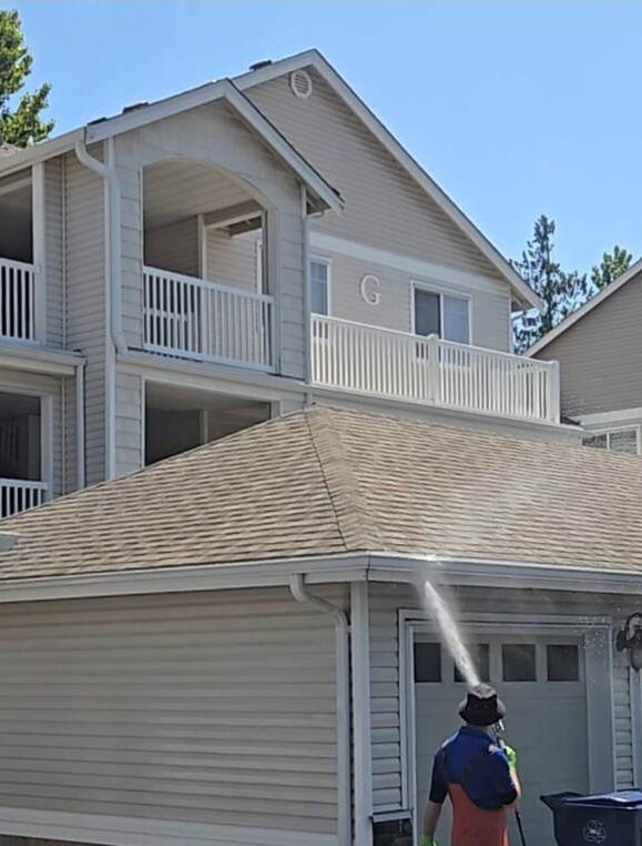 Deep Water technician pressure washing the garage and siding of a Seattle home