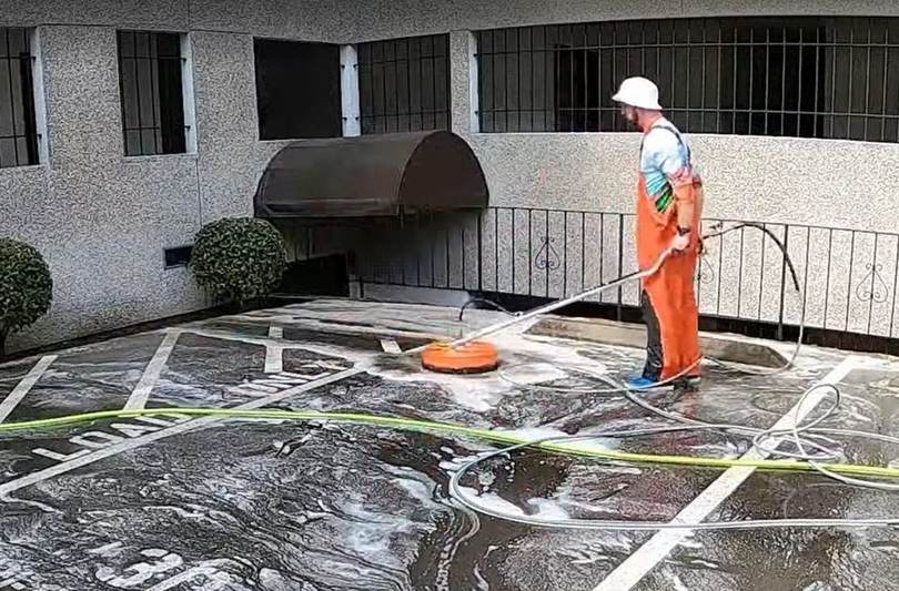 Technician surface cleaning a commercial parking court