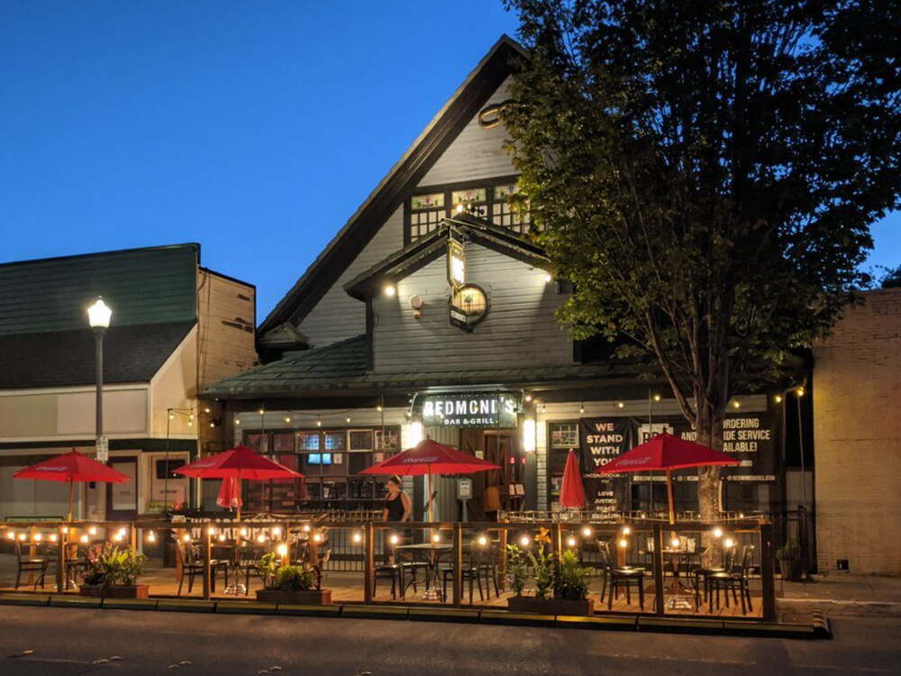 Redmond restaurant patio with red umbrellas and string lights at dusk