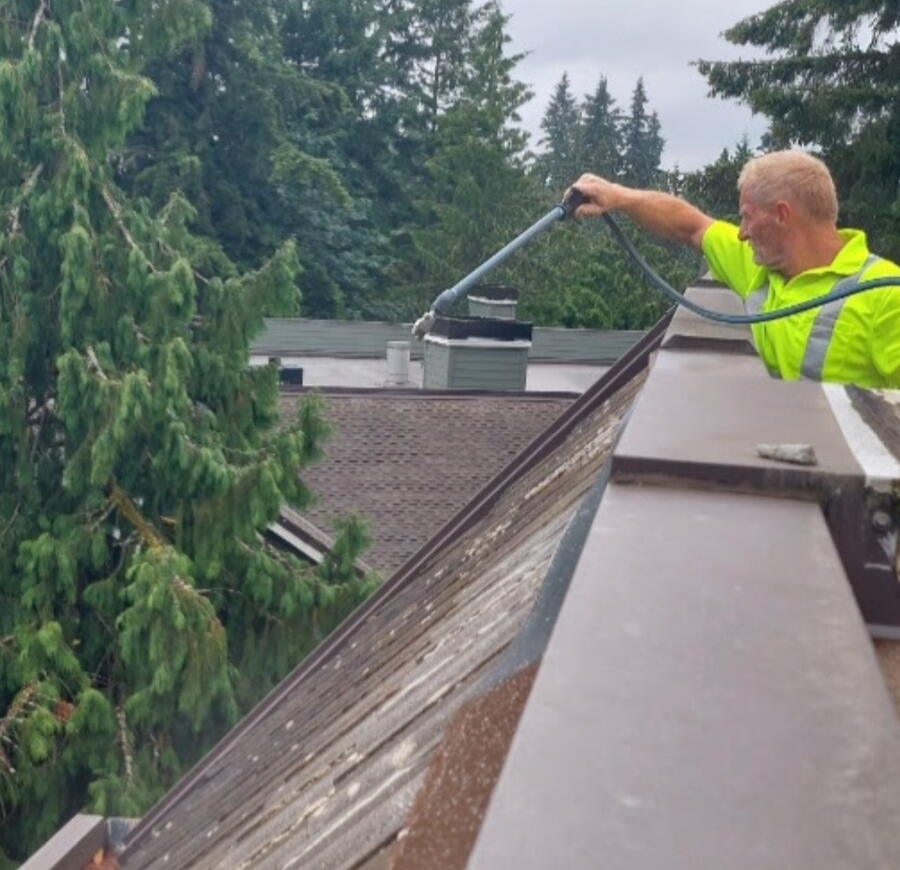 Deep Water technician soft washing a commercial roofline in Redmond