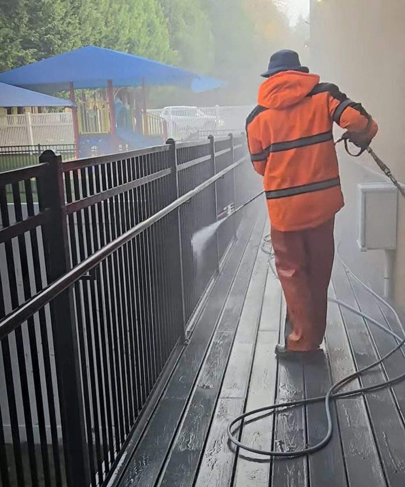 Technician pressure washing a commercial walkway and railing