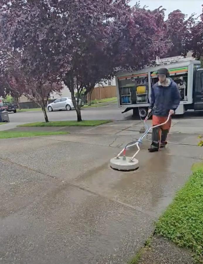 Technician surface cleaning a concrete driveway