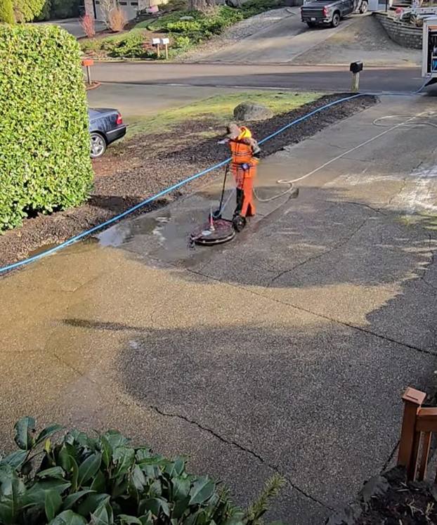 Technician surface cleaning a driveway with the Deep Water rig parked nearby