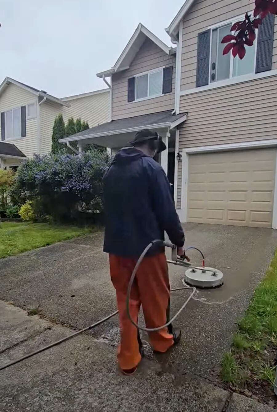 Deep Water technician cleaning a home driveway with a rotary surface cleaner