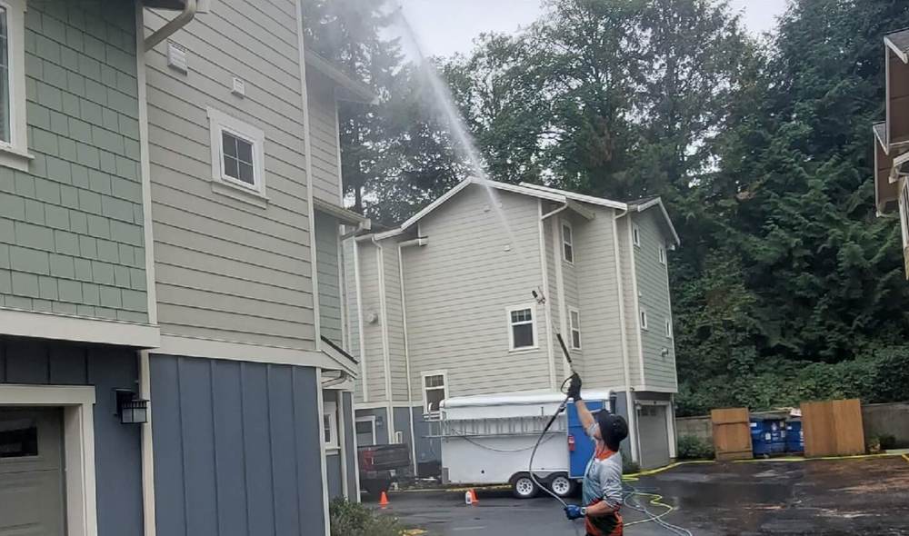 Deep Water technician soft washing the siding of a row of Capitol Hill townhomes