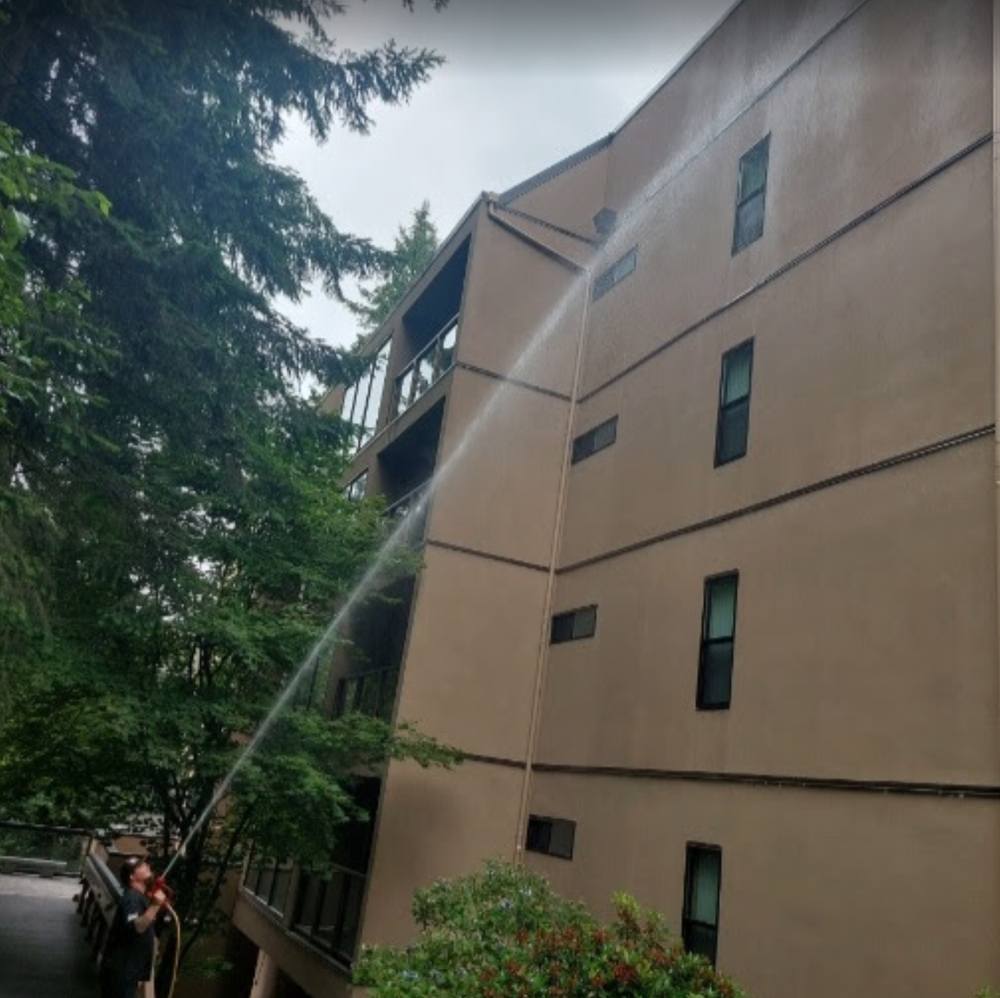 Deep Water technician soft washing the upper stories of a Bellevue commercial building