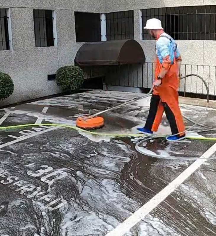 Deep Water technician surface cleaning a commercial parking area with a rotary surface cleaner