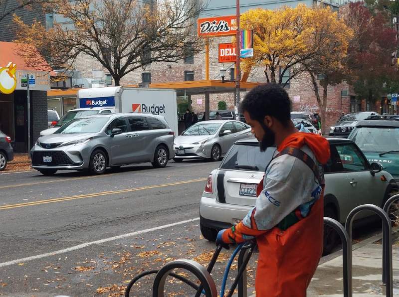 Deep Water technician pressure washing a Seattle storefront sidewalk